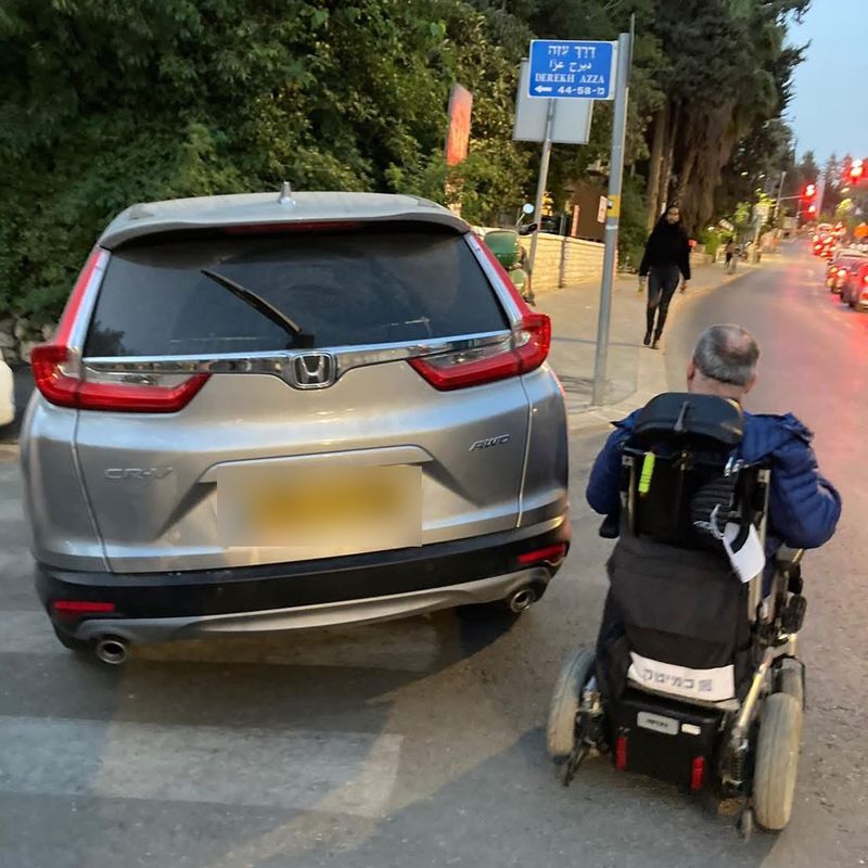 רכב חונה על מעבר חציה, ואדם בכיסא גלגלים נאלץ לנסוע בכביש לצידו